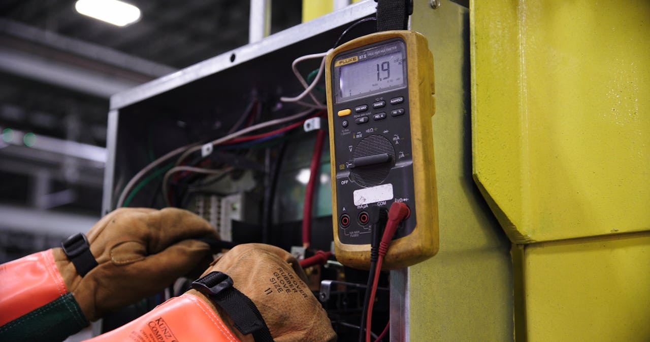 services-04 Electrician using a multimeter to fix industrial control panel wiring.