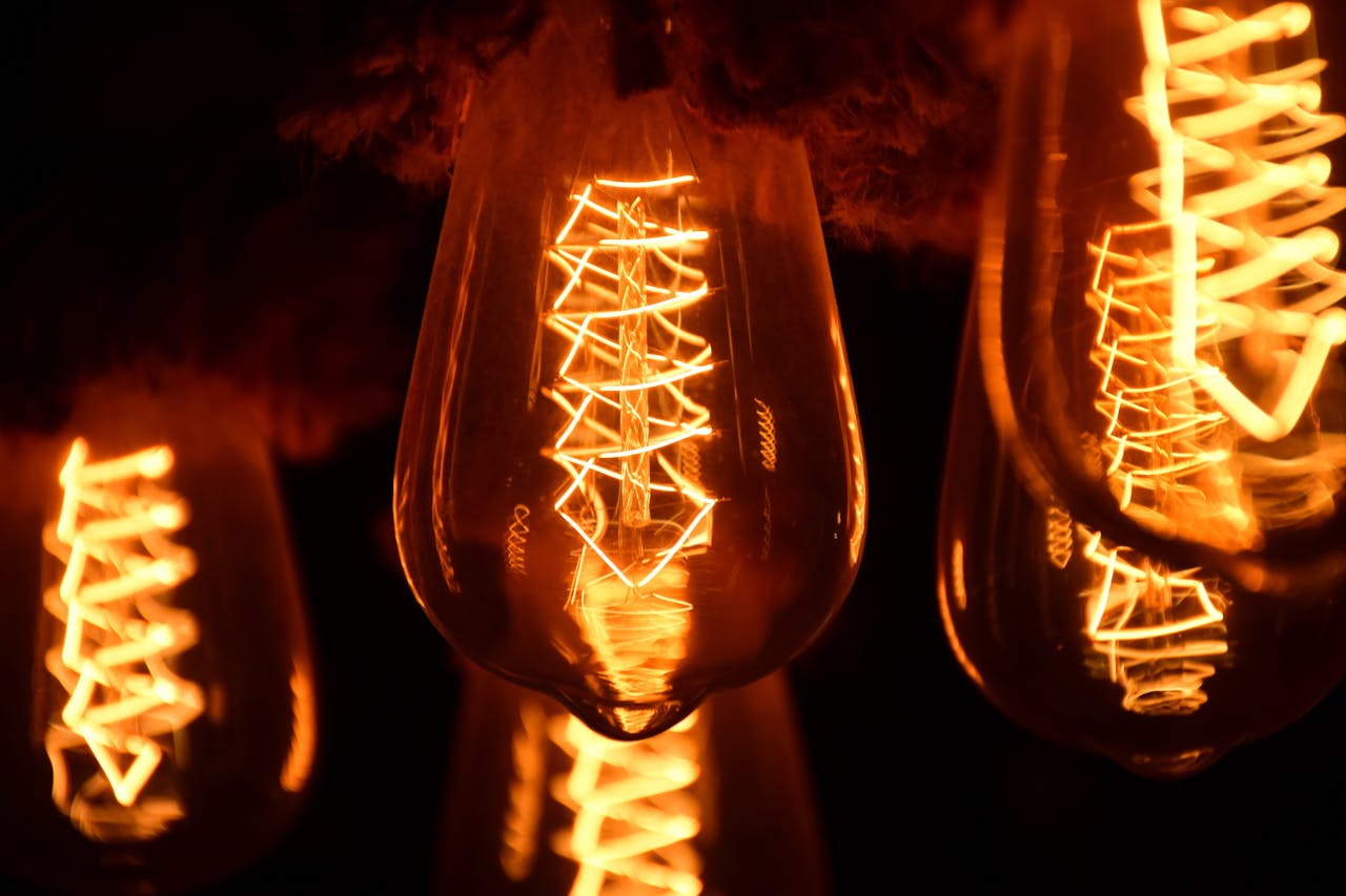 services-02 A close-up image of glowing vintage Edison light bulbs showcasing intricate filaments.