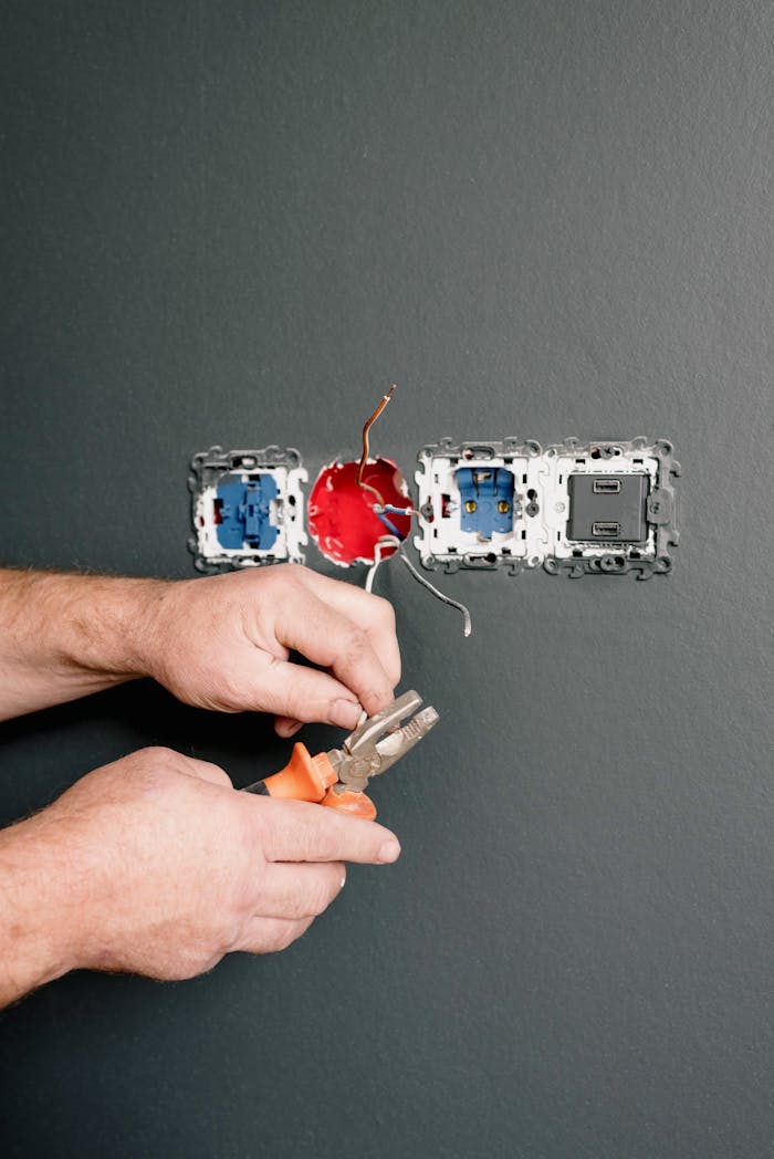 services-01 Crop faceless electrician using pliers for installation sockets and switches in new apartment